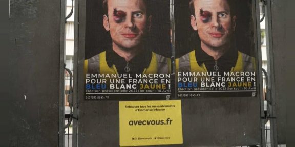 Emmanuel Macron apparait sur cette affiche avec un gilet jaune et un œil au beurre noir, clin d’œil aux violences policières - Copyright © africanews cleared