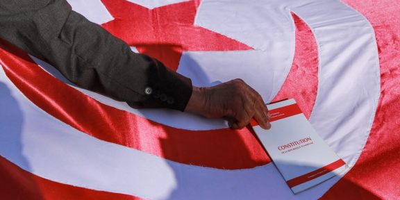 Lors d'une manifestation d'Ennahdha à Tunis, un homme place une copie de la constitution tunisienne sur le drapeau national.